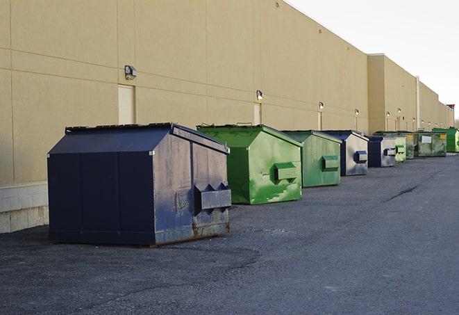 a pile of demolition waste sits beside a dumpster in a parking lot in Morrison